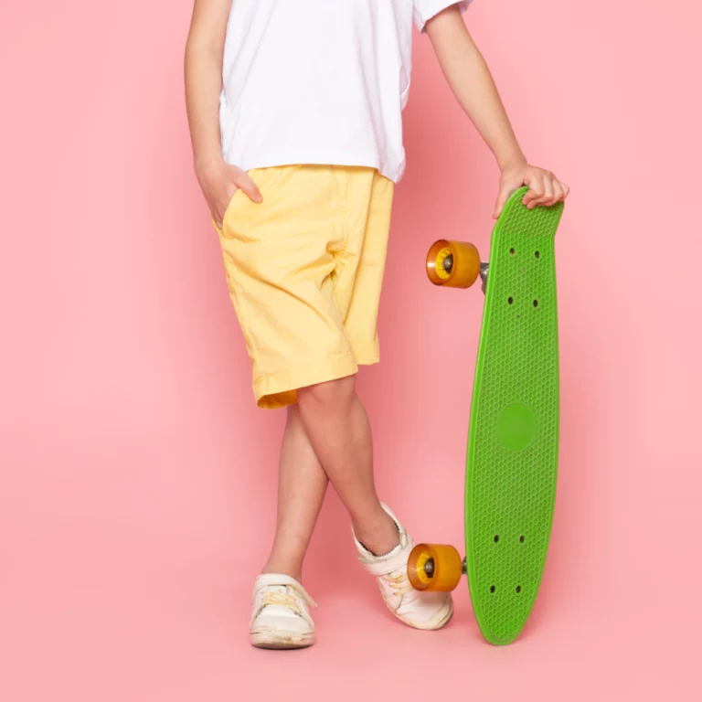 front-view-cute-smiling-boy-white-t-shirt-yellow-jeans-holding-green-skateboard-pink-space