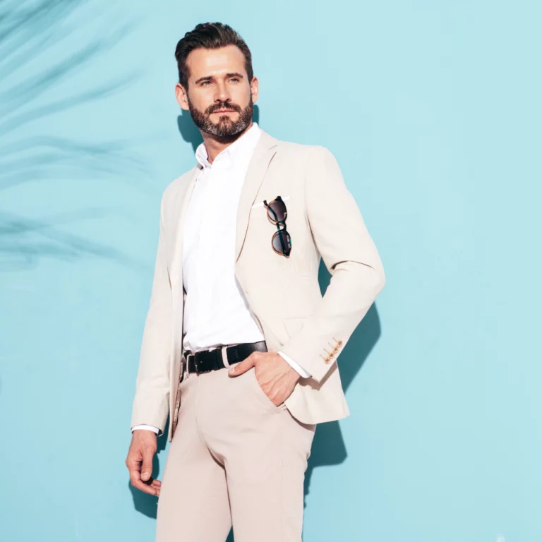 portrait-handsome-confident-stylish-hipster-lambersexual-model-sexy-modern-man-dressed-white-elegant-suit-fashion-male-posing-studio-near-blue-wall-sunglasses